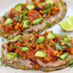 huaraches de nopal on a beige plate with avocado and salsa on top.