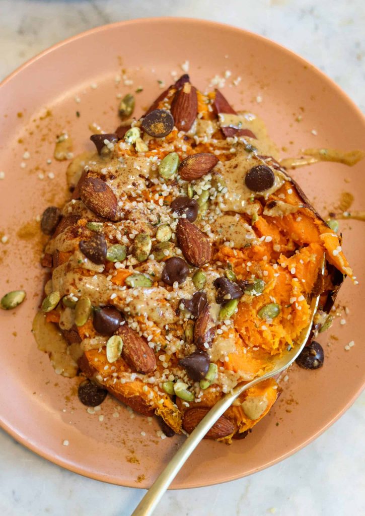 sweet potato with toppings on a pink plate.