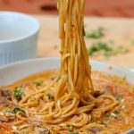 peanut ramen noodles in a white bowl.