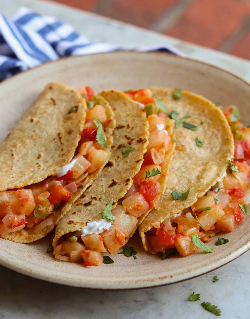 mexican potato tacos on a beige plate.