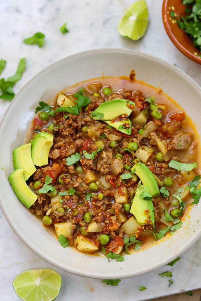 vegan mexican picadillo in a white bowl with avocado and cilantro on top.