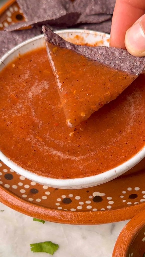 chip being dipped in a mexican salsa in a bowl.